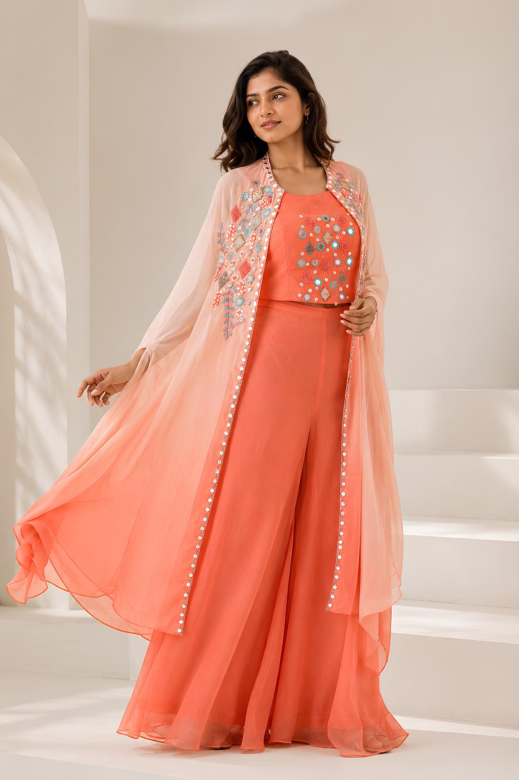 Peach Shrug Set in Chinon Crepe with Mirror & Thread Work Women's peach embroidered shrug set with flowing jacket and flared silhouette from Mansa Sarees
